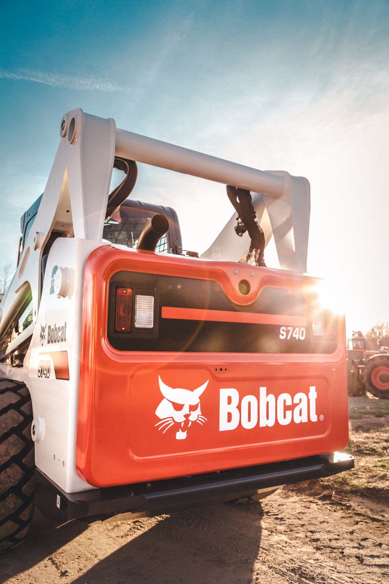 Bobcat skid steer loader parked outdoors with clear sky and sunny backdrop