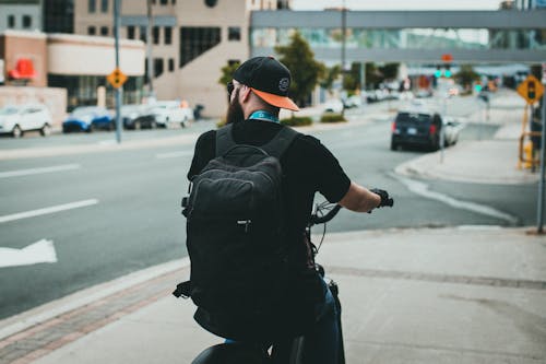 Man Carrying Black Backpack While Riding a Bicycle