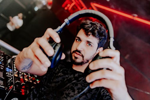 A Bearded Man in Black Shirt Holding His Headphones