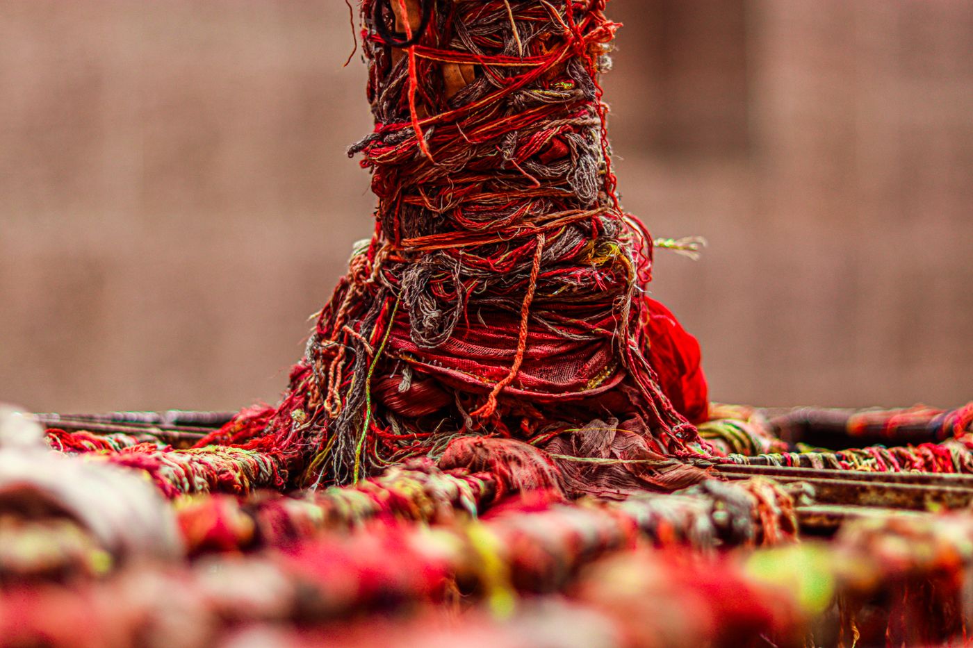 Red yarn wound around a wooden post on a traditional loom, photographed by Swastik Arora on Pexels