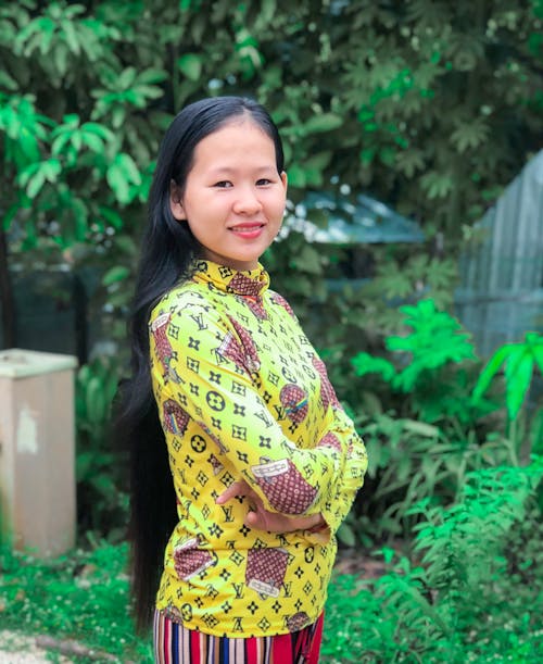 A Woman in Yellow Turtleneck Sweater Smiling with Her Arms Crossed