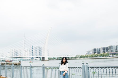 A Woman in White Long Sleeves Standing Near the Metal Railing