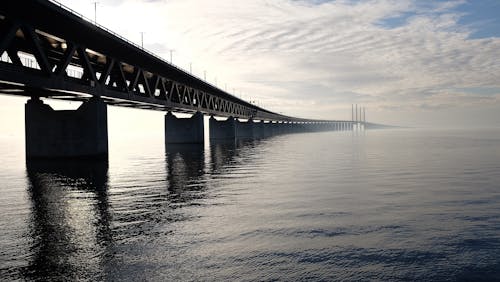 免费 白天在蓝色和白色的天空下的水体上的灰色混凝土桥 素材图片