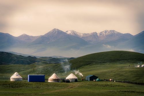 Free A serene yurt camp nestled in a lush green landscape with majestic mountains in the background. Stock Photo