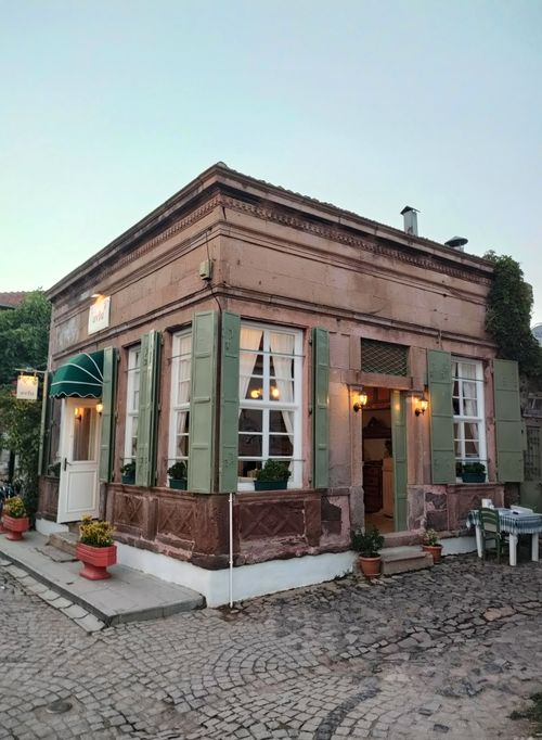 Free Vintage cafe on a cobblestone street with green shutters and warm lighting. Stock Photo
