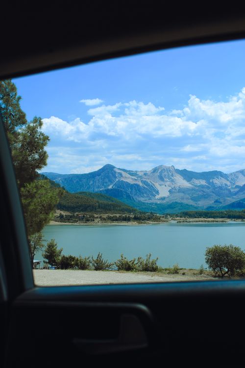 Free Serene view of mountains, lake, and blue sky captured from inside a car Stock Photo