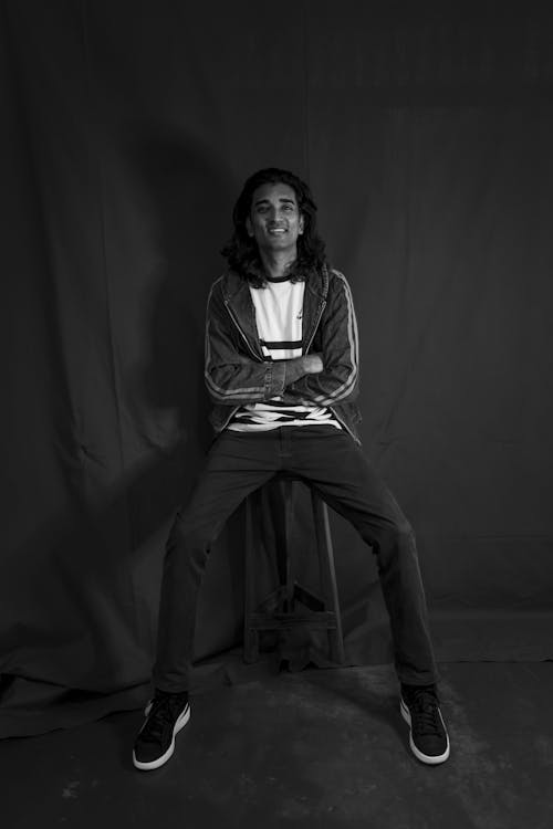 Grayscale Photo of a Person Sitting on a Stool