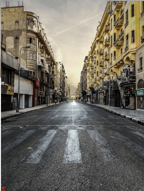 Carretera De Asfalto Negro Entre El Edificio De La Ciudad Marrón Bajo Un Cielo Blanco Durante El Día