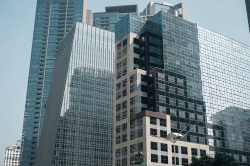 Free A striking view of modern glass skyscrapers reflecting the urban cityscape under a clear sky. Stock Photo