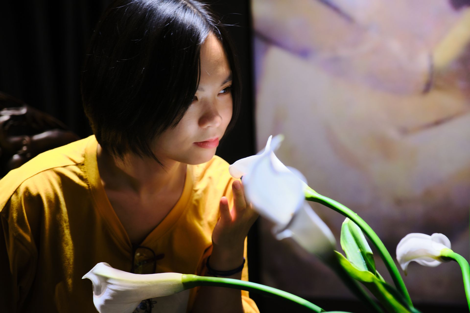 A serene woman gently holds white calla lilies, framed by a blurred background, evoking a peaceful mood.