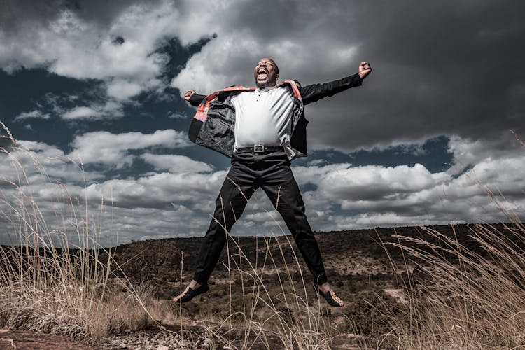 Happy Man Wearing SUit Jumping On Field