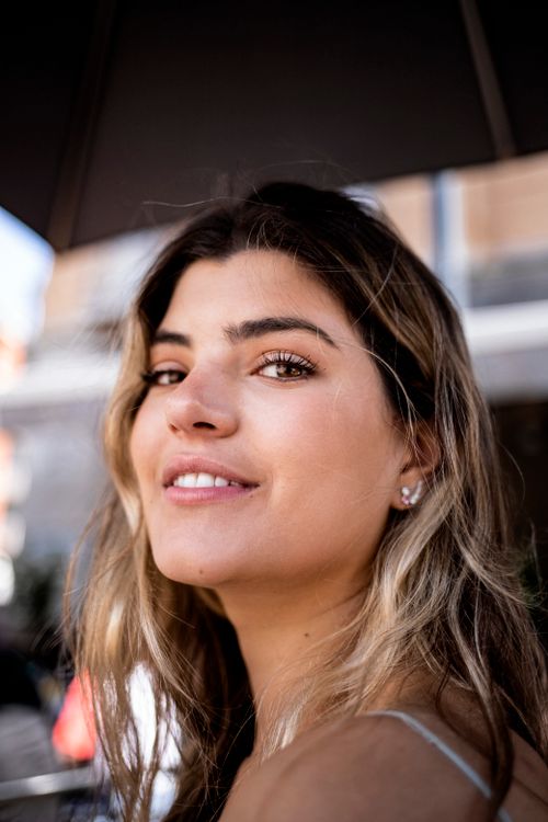 Free Portrait of a smiling young woman enjoying a sunny day outdoors in Milan. Stock Photo