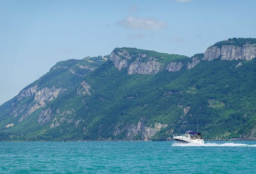 A Sailing Boat on the Sea Near the Mountain with Green Trees