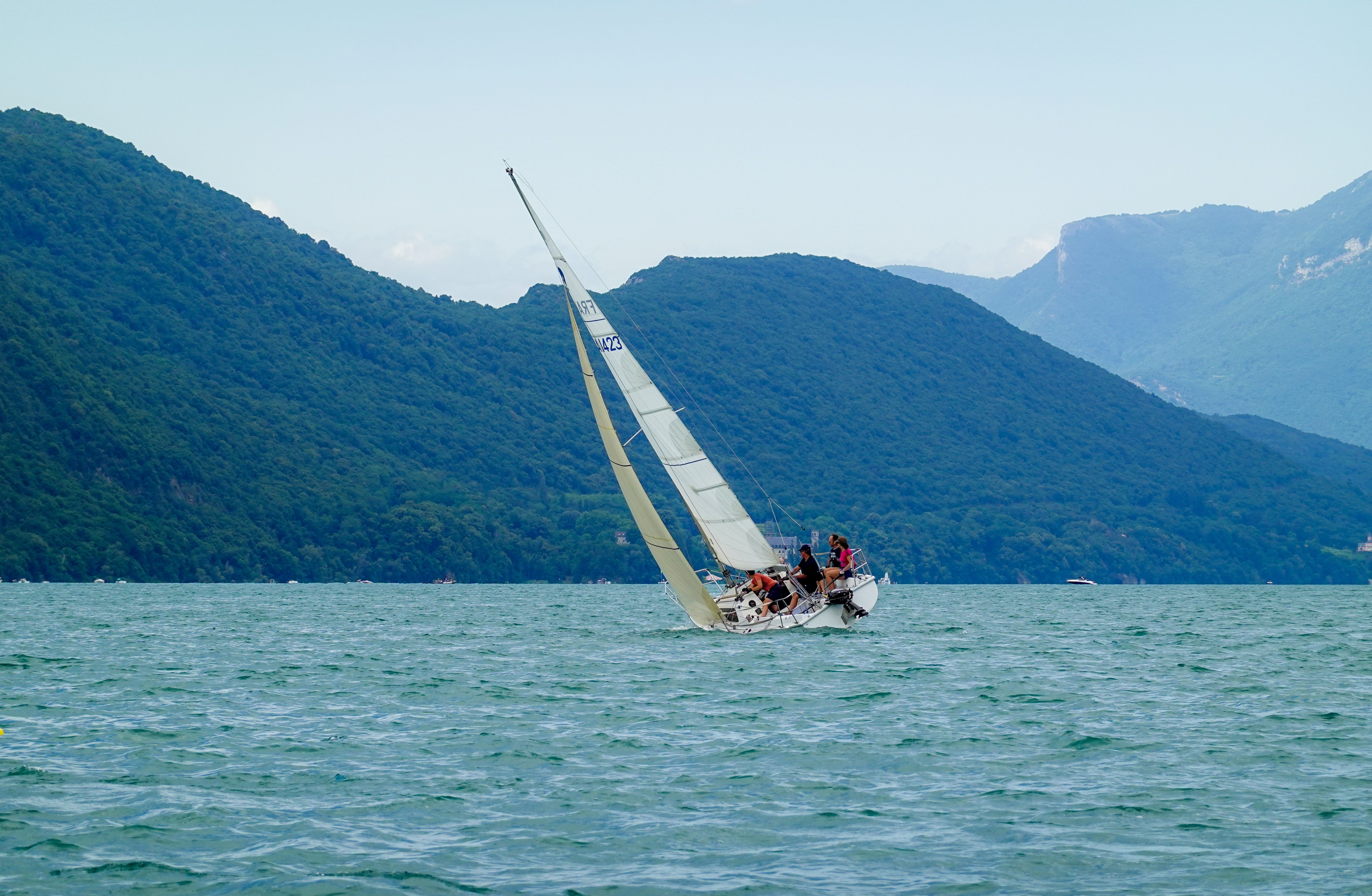 People Riding on a Sailing Boat on Sea Near the Mountain · Free Stock Photo