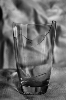 A broken glass captured in a close-up black and white still life image.