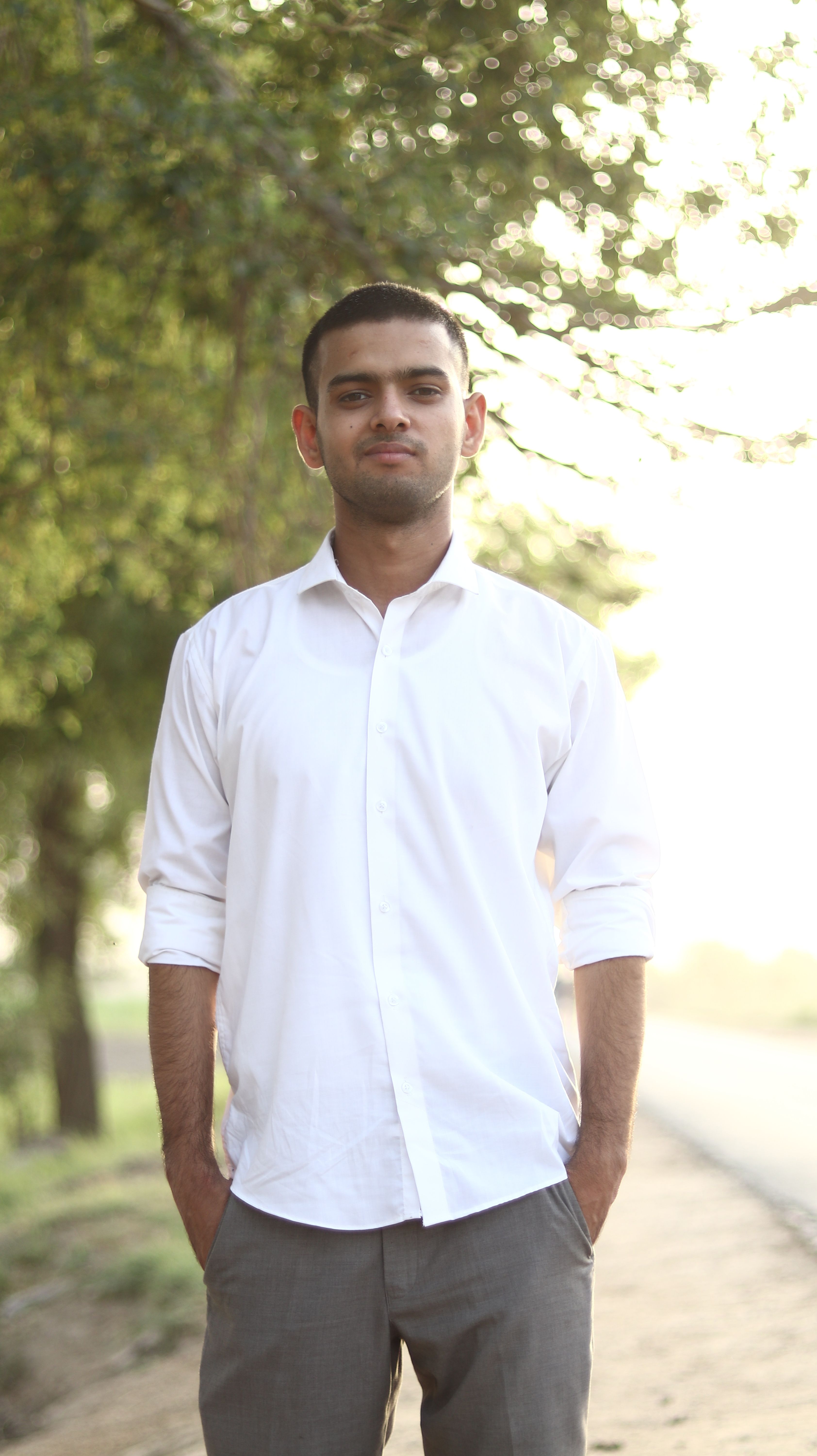 Young man in white shirt enjoying a sunny day outdoors, relaxed and stylish.