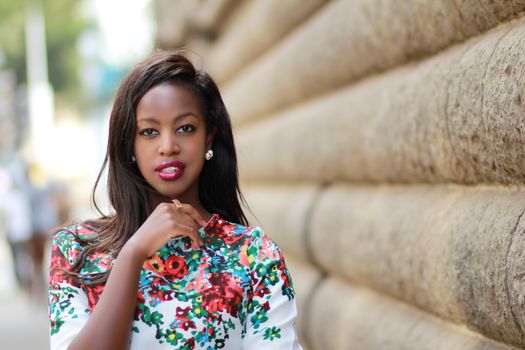 Young Brunette Woman Wearing Floral Patterned Blouse Posing by a Wall