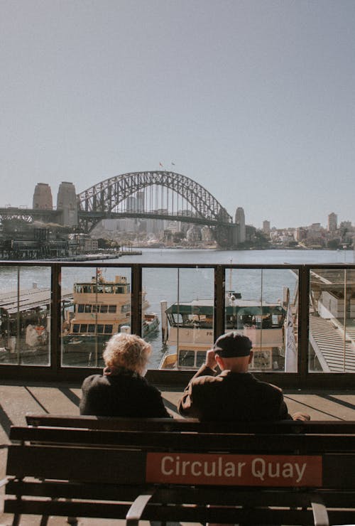 Elderly Couple Sitting on Bench Near Harbor 