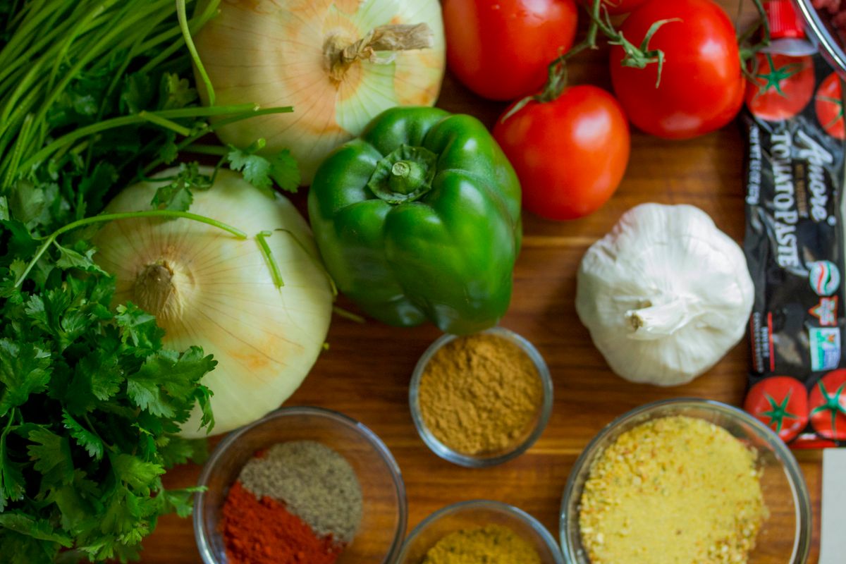 Fresh vegetables and plant-based ingredients arranged on a kitchen table for vegetarian meal preparation
