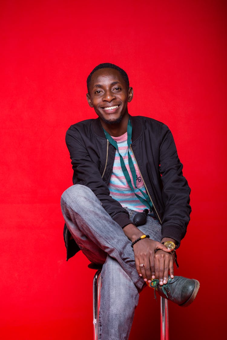 Smiling Man Sitting On Chair In Studio