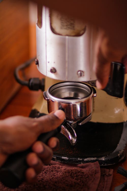 Photo of a Hand Putting a Portafilter under a Coffee Grinder