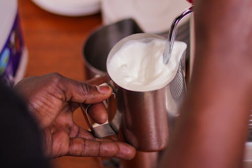 A Person Holding a Stainless Container with Milk