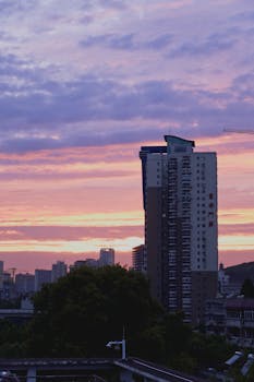 A serene urban skyline with residential towers silhouetted against a colorful sunset sky.