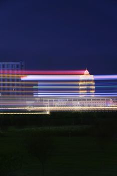 Urban night scene with motion blur light trails and modern architecture.
