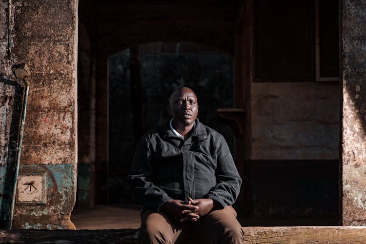 Overweight Man Sitting At Neglected Building