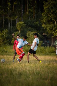 Young men enjoy a soccer match outdoors in casual sports attire on a grassy field.