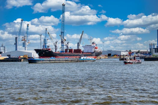 Cargo ships and cranes in a busy harbor under a vibrant blue sky.