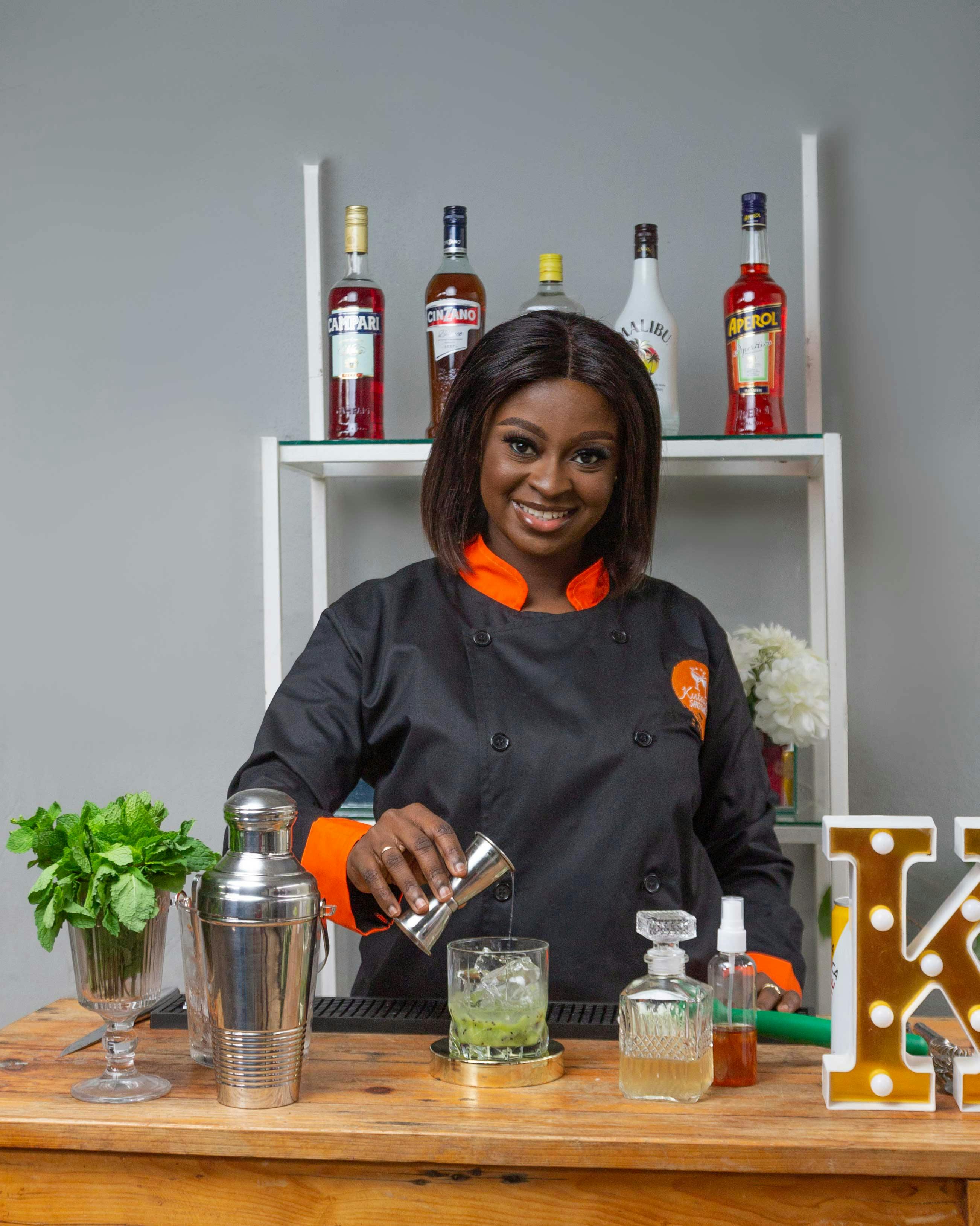 Smiling bartender in uniform crafting a cocktail at a bar counter.