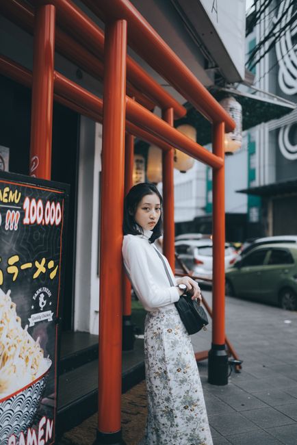 Fashionable Asian woman standing before vibrant urban backdrop in Jakarta.