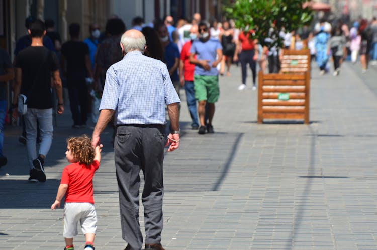 Grandfather And Child Walking On The Street 