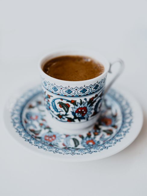 An ornate coffee cup with intricate blue and red patterns on a matching saucer.