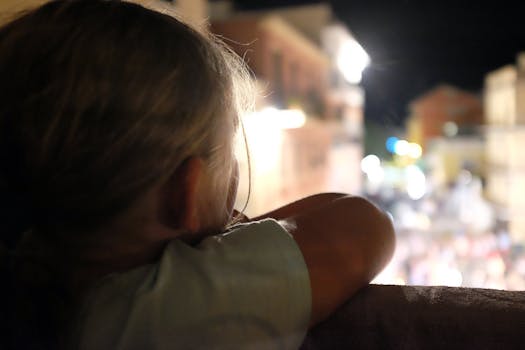 夜晚，一名年轻女孩眺望着城市街道，街上灯光璀璨，人群熙攘