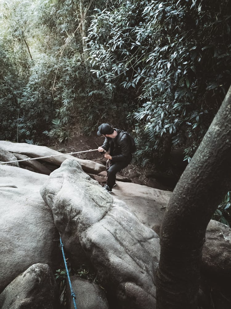 Man Climbing On A Steep Rock Using A Rope 