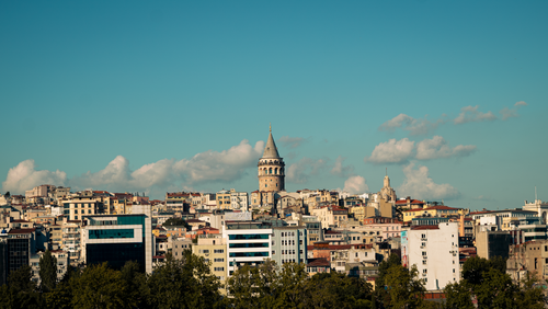 Free View of the iconic Galata Tower surrounded by Istanbul's urban landscape under a blue sky. Stock Photo