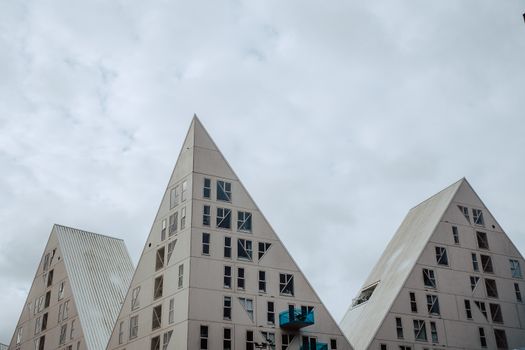 Triangular residential buildings showcase modern architectural design against a cloudy sky.