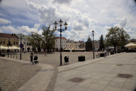 Sunny day in a charming European town square with people and historic buildings.