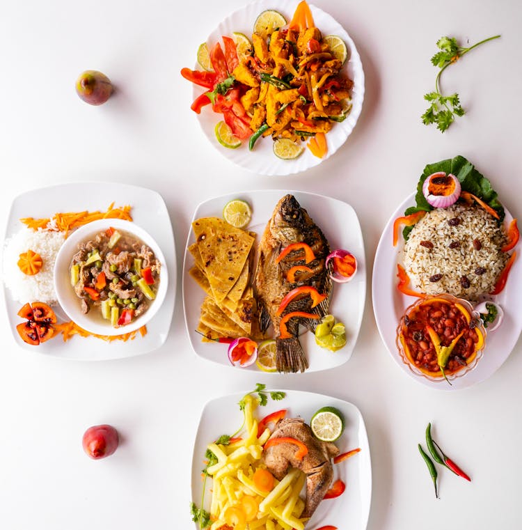 A Variety Of Cooked Foods On Ceramic Plates