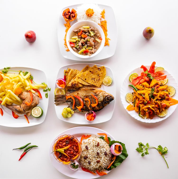 A Variety Of Cooked Foods On Ceramic Plates