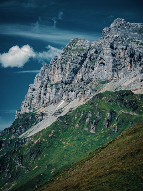 Free A breathtaking view of rugged mountains and green slopes under a vibrant blue sky, perfect for nature enthusiasts. Stock Photo