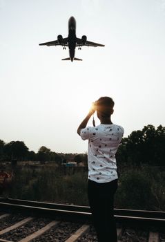 A low-flying airplane over a photographer standing on railway tracks in New Delhi during daytime.