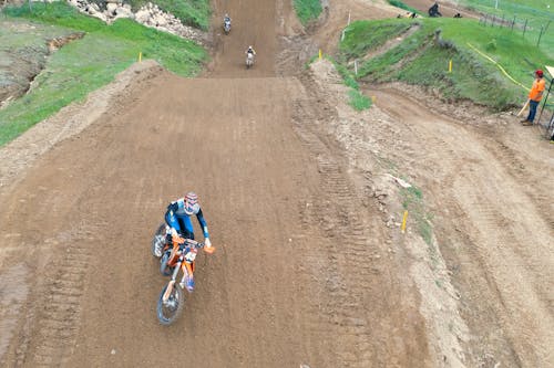 Man in Blue and Black Motorcycle Suit Riding Motocross Dirt Bike on Dirt Road