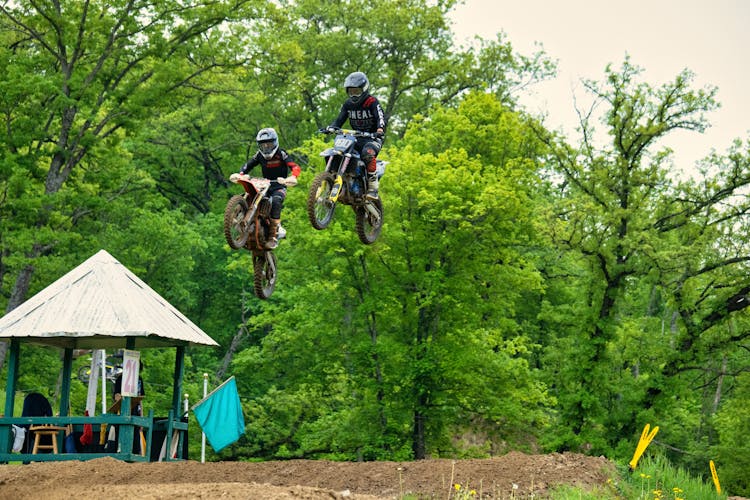 Men Riding Motocross Dirt Bike Over A Ramp