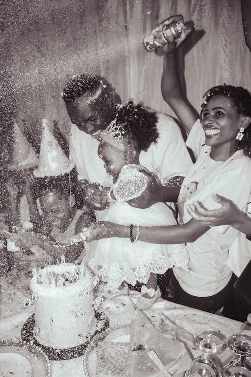 Free Happy family celebrating a birthday with cake and confetti indoors. Laughter and joy fill the atmosphere. Stock Photo Free Happy family celebrating a birthday with cake and confetti indoors. Laughter and joy fill the atmosphere. Stock Photo