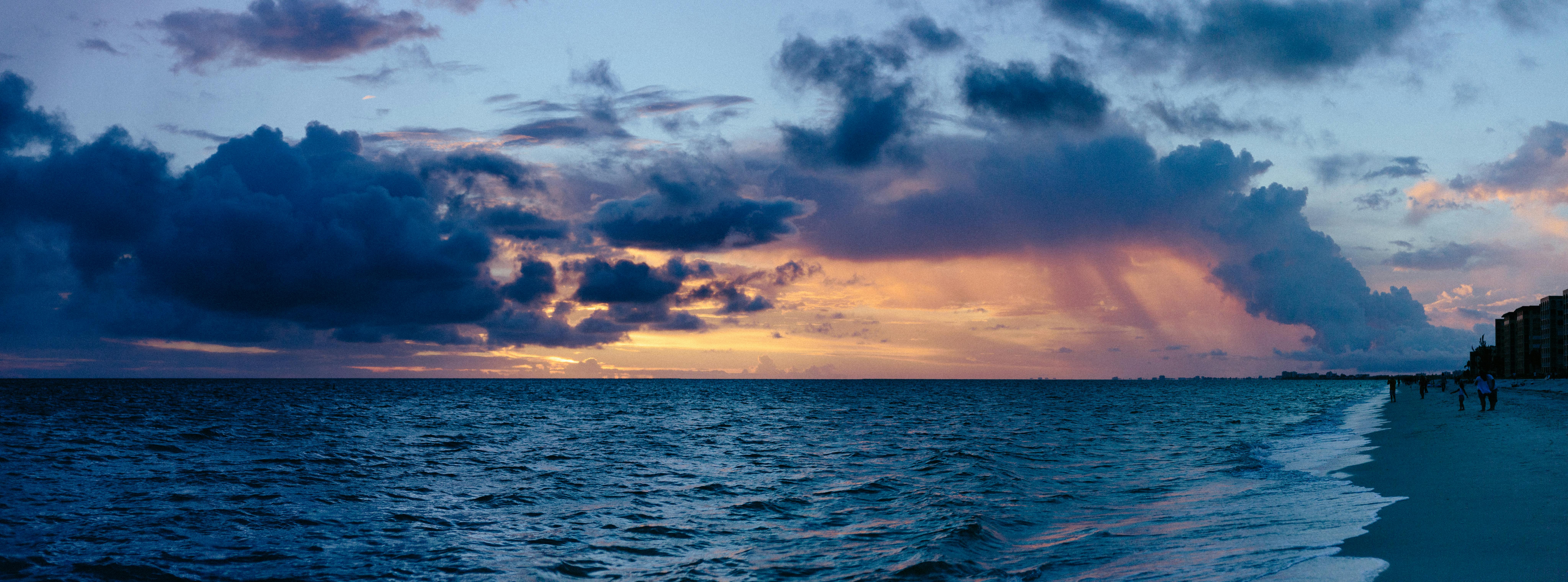 海洋与沙滩上空，充满活力的云和温柔的海浪映衬着一个令人叹为观止的日落