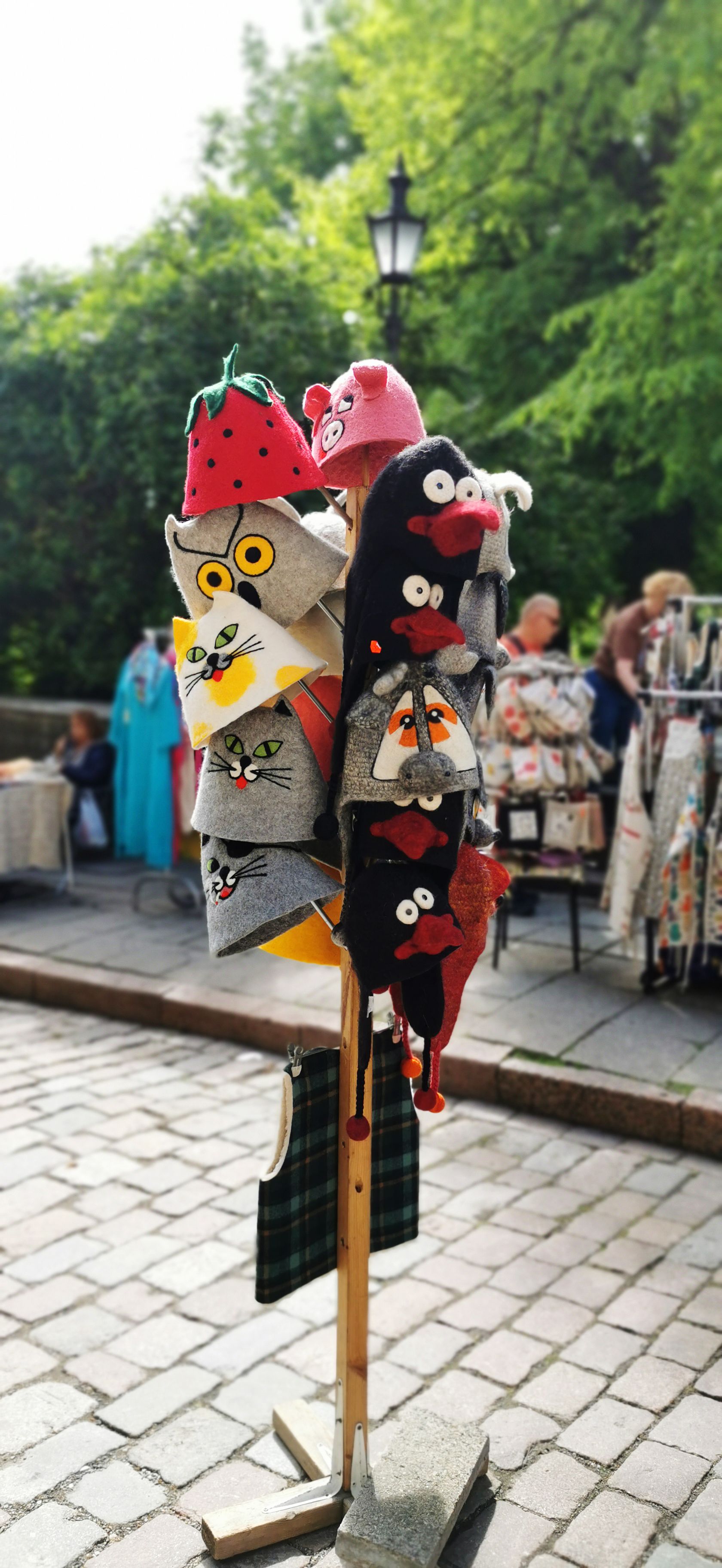 Vibrant collection of cartoon-themed hats showcased outdoors at a Tallinn street market.