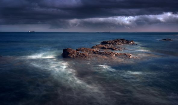 Ocean Waves Crashing on Rocks Under Cloudy Sky